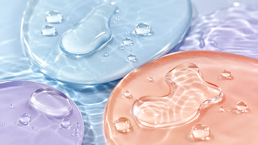  Gouttes de sérum transparent sur des formes pastel évoquant le pouvoir humectant de la glycérine pour la peau.