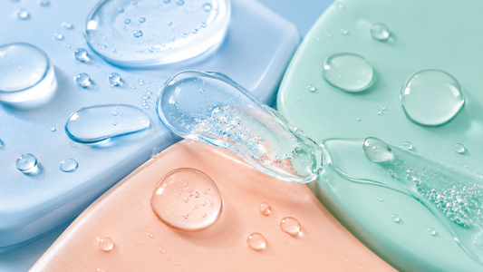 Gouttes d’eau et gel transparent sur des formes pastel illustrant un soin hydratant à la bétaïne.