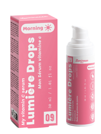 Packshot de Lumière Drops n°09 de Luminesse Paris avec son étui rose et son flacon pompe blanc de 30 ml. Le produit et la boîte sont présentés côte à côte sur fond transparent ; la mention Morning ainsi que les références à la vitamine C, vitamine E et huile de graines de jojoba sont visibles.