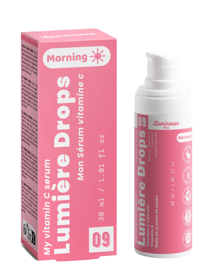 Packshot de Lumière Drops n°09 de Luminesse Paris avec son étui rose et son flacon pompe blanc de 30 ml. Le produit et la boîte sont présentés côte à côte sur fond transparent ; la mention Morning ainsi que les références à la vitamine C, vitamine E et huile de graines de jojoba sont visibles.